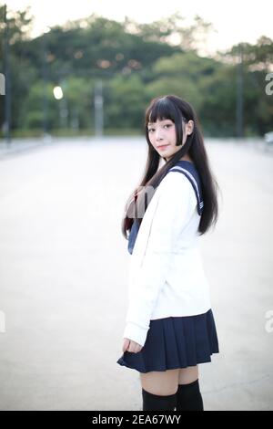 Asian school girl walking in urban city with green darden Stock Photo