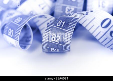 Measuring tape, coiled. Image toned in blue, close-up. Stock Photo