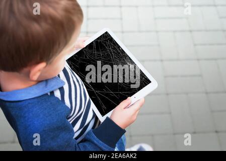 Broken tablet in boy hands concept. Smashed screen after drop Stock Photo