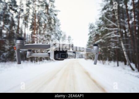 Drone quadcopter with camera flying in the winter forest Stock Photo