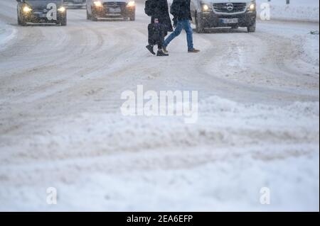 08 February 2021, Lower Saxony, Osnabrück: Pedestrians walk across a main street covered with snow. Photo: Jonas Walzberg/dpa Stock Photo