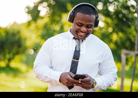 Portrait of happy african-american businessman who is using smartphone. Stock Photo