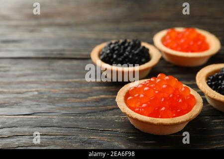 Tartlets with red and black caviar on wooden background, space for text Stock Photo