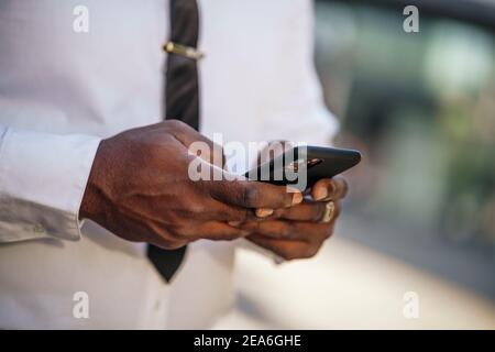 Close up of african-american businessman who is using smartphone. Stock Photo