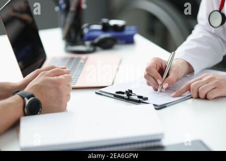 Doctors hands writing down patients complaints in medical history closeup Stock Photo