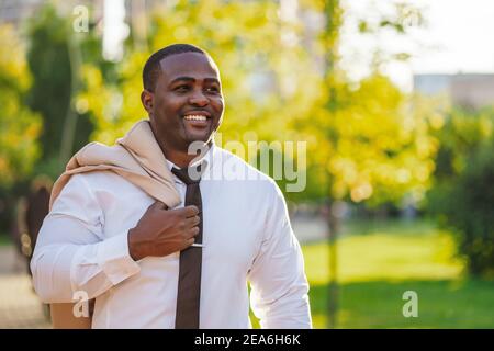 Portrait of happy african-american businessman who is walking in park. Stock Photo