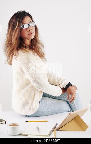 Woman sitting on desk with textbooks Stock Photo