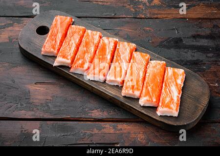 Crab sticks seafood semi finished fish mince with blue swimming crab, on wooden cutting board, on dark wooden background Stock Photo