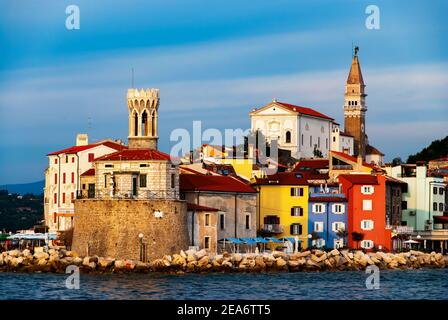 Colorful picturesque houses, towers and church on Presern embankment in medieval city Piran, Slovenia. Stock Photo
