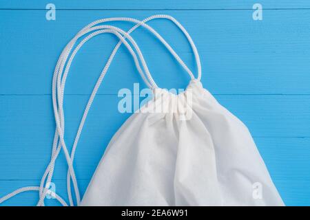 Knotted Rope Tied Closed Synthetic Textile Bag Close Up On Wooden Plank Blue Background. Delivery Concept Stock Photo