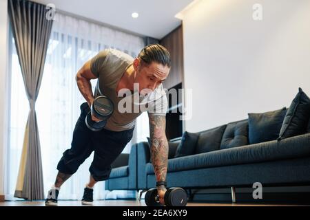Man doing dumbbells plank row exercise Stock Photo