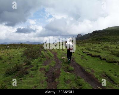 Lalibala-Ethipia - April 10, 2019: Man with sack walking in green field in Ethiopian highlands Stock Photo