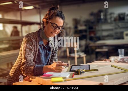 Middle age creative designer in her making studio doing through paper plans. Late night work. Stock Photo