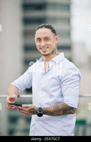 Smiling mixed-race man texting Stock Photo
