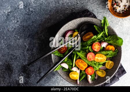 Bowl of fresh rocket salad with cherry tomatoes and red onion Stock Photo