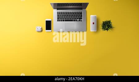 Flat lay top view office desk working space with laptop on yellow background. Copy space. Stock Photo