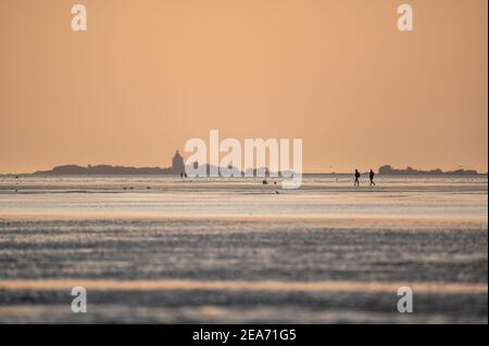 People at sunset in the wadden in Cuxhaven at sunset - Menschen im Watt von Cuxhaven im Sonnenuntergang Stock Photo