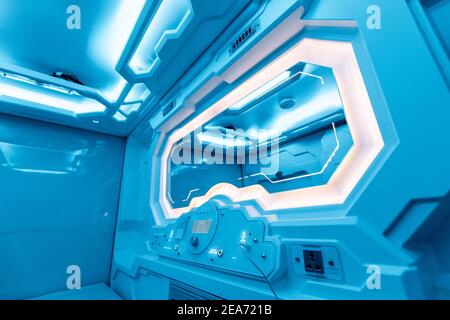Inside a small cozy room in a capsule hotel - a futuristic interior with a light control panel, electric charging and an alarm clock filled with calm Stock Photo