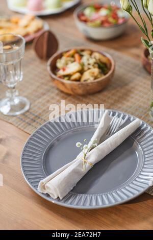 Close up background of elegant rustic dinner table set with delicious homemade food, place setting in foreground, copy space Stock Photo