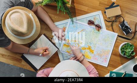 Top view of young couple with maps planning vacation trip holiday, desktop travel concept. Stock Photo