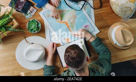 Top view of young couple with maps planning vacation trip holiday, desktop travel concept. Stock Photo