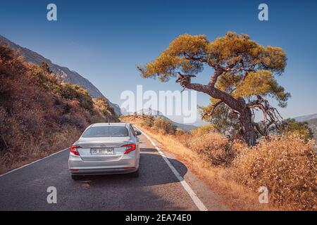 12 September 2020, Termessos, Turkey: Car driving by a picturesque narrow paved road in the Termessos National Park in Turkey. Beautiful red colors of Stock Photo