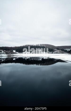 Beautiful view of a lake surrounded by trees covered in snow in Brocken Harz, Germany Stock Photo