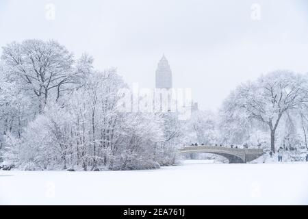 Snowy Central Park with people standing on a bridge in New York City, New York. Stock Photo