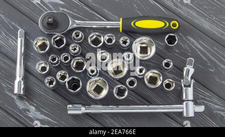 Interchangeable nozzles with a ratchet key on a gray wooden background. Stock Photo