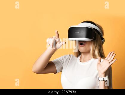 Portrait of woman in white t-shirt using VR glasses exploring augmented reality pressing virtual button with finger Stock Photo