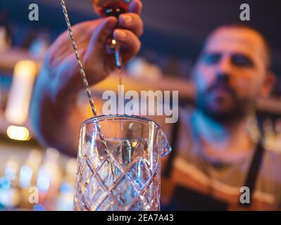 Barman pouring alcohol into empty glass to make drink in pub Stock Photo