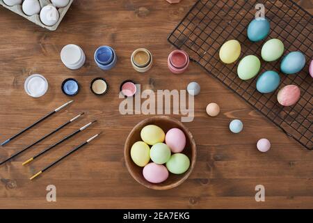 Top view background of pastel colored Easter eggs on wooden table and art supplies, DIY Easter decorations, copy space Stock Photo