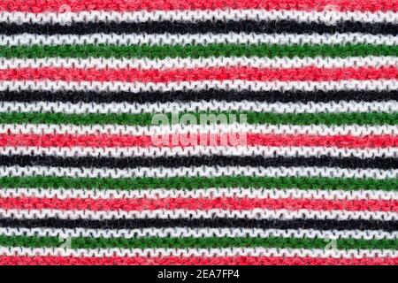 Close-up of hand made knitted stitch wool pattern in red, white, black and green.