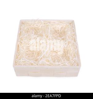 Top view of wooden box for eco gift filled with decorative shredded white paper with four holes for gifts. Isolated on white, clipping path included. Stock Photo
