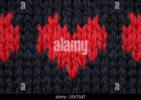 Knitted red hearts made of yarn on a black background. Stock Photo