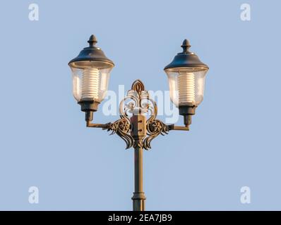 Detail of a street lamp or lamp post with two white globes and led light bulbs against ble sky. Stock Photo