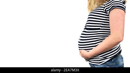 side view of midsection of 9 months pregnant woman in striped top an jeans with hands on belly against white background Stock Photo
