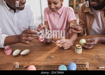 Happy African-American family painting Easter eggs together while sitting at wooden table and bonding over DIY project, copy space Stock Photo