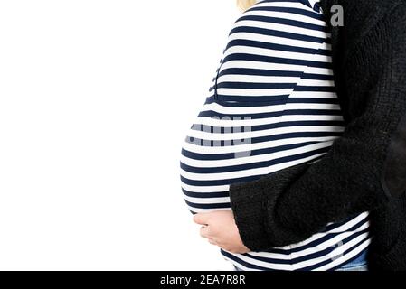 close-up side view of baby bump of nine months pregnant woman wearing striped top and wool cardigan against white background
