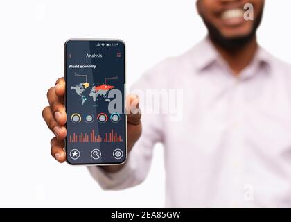 Unrecognizable Black Man Holding Smartphone With World Economy Analysis App On Screen Stock Photo
