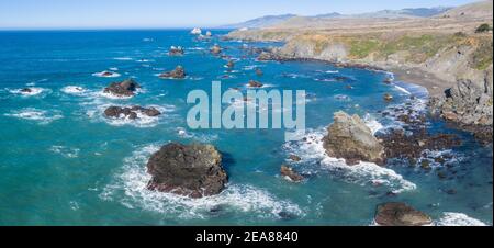 The Pacific Ocean washes against the shoreline of northern California on a beautiful day. The scenic Pacific Coast Highway runs this coastal area. Stock Photo