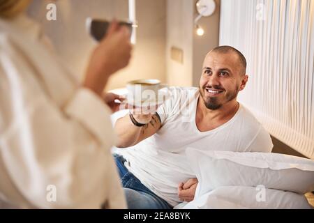 Pleased married man being served coffee in bed Stock Photo