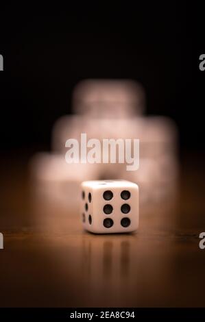 Isolated dice showing a six in front of stack of dice on dark background Stock Photo