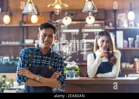 Portrait of Asian Young Small business owner with coffee shop in front of counter bar, entrepreneur and startup, preparing for service to customer in Stock Photo