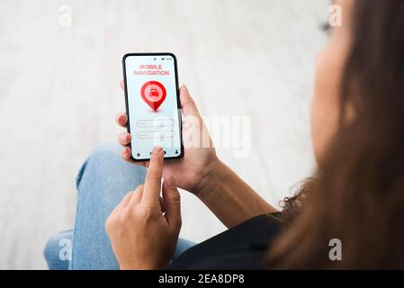 Woman Using Smartphone With Mobile Navigation Application Sitting Indoors Stock Photo