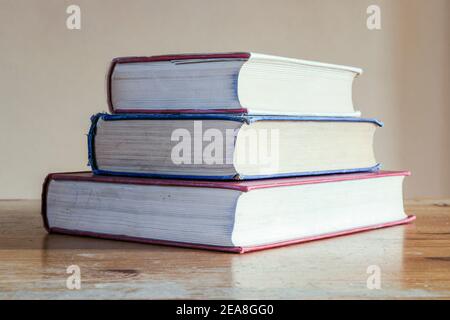 A stack of three old hardback reference books on an old wooden desk Stock Photo