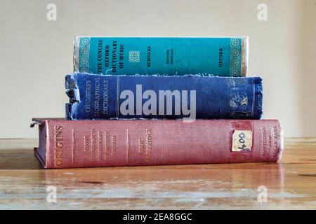 A stack of three old hardback reference books on an old wooden desk Stock Photo