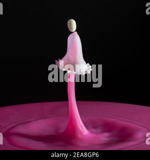 High speed shot of milk drops colliding and creating a splash in pink and white Stock Photo