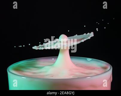 High speed shot of milk drops colliding and creating a splash in green and pink colours Stock Photo