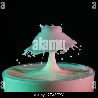 High speed shot of milk drops colliding and creating a splash in green and pink colours Stock Photo